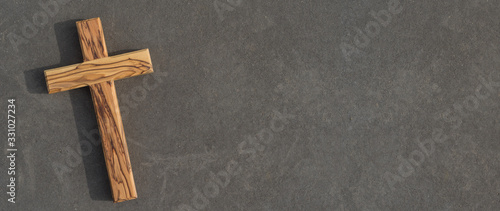 Fotomural Holzkreuz liegt auf dunkler Steinplatte