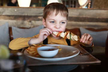 Child eating meat and vegetable kebab