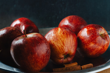 Wall Mural - Autumn colors. Red apples with some cinnamon sticks on a steel tray on black backgraund. Chiaroscuro. space for text.