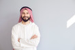 © Studio Romantic - Attractive smiling arab man crossed his arms on a gray background