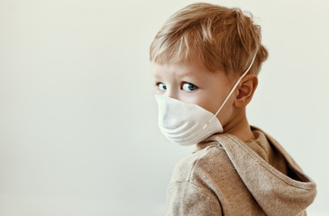 Boy in medical mask looking over shoulder.