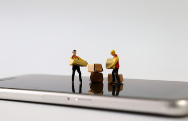 Two miniature couriers standing on top of a Smartphone.