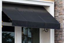 Black Awning Over White Window Frame Of Shop.