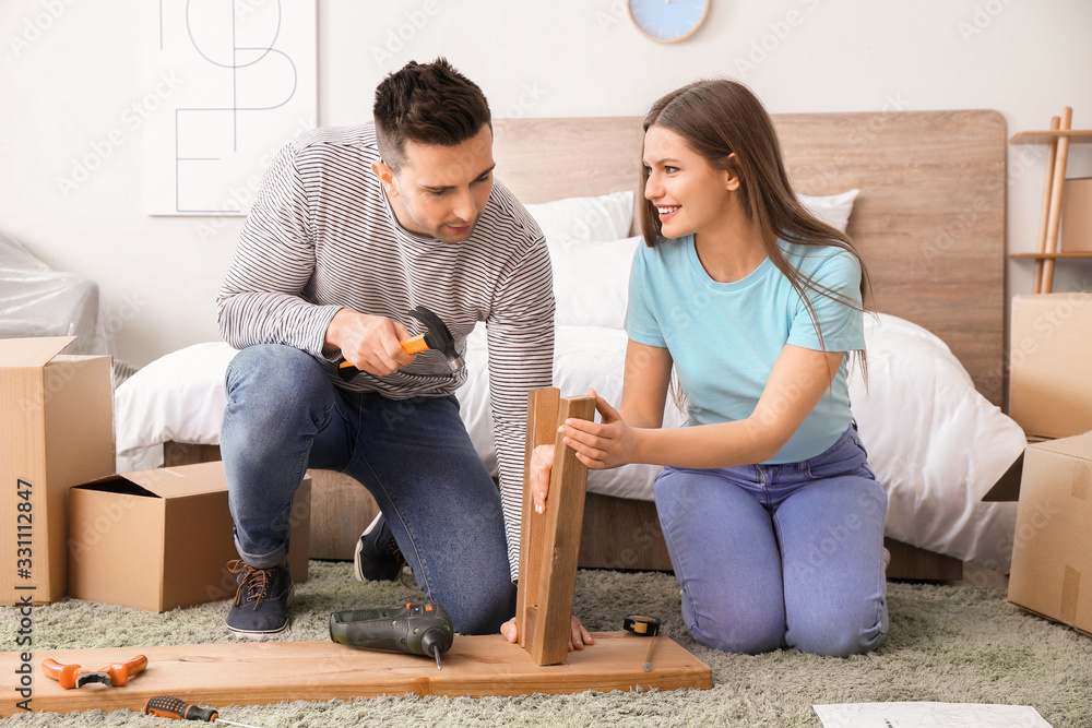 Young couple assembling furniture at home