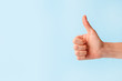 © misskaterina - Closeup of female hand showing thumbs up sign against pastel blue background, copy space, minimal concept