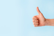 Closeup Of Female Hand Showing Thumbs Up Sign Against Pastel Blue Background, Copy Space, Minimal Concept