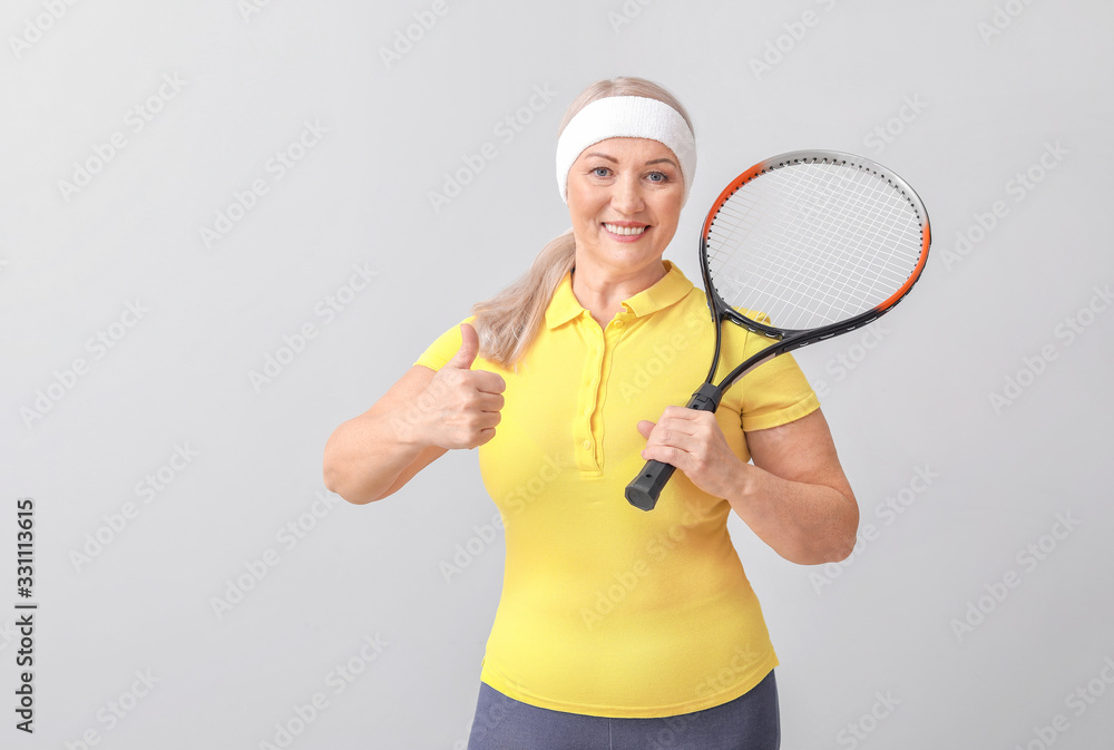 Mature female tennis player on light background