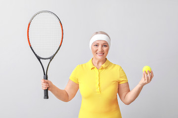 Mature female tennis player on light background