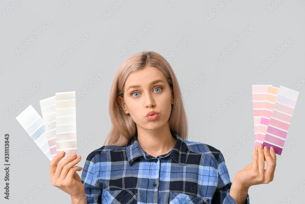 Troubled woman with color swatches on grey background
