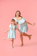 © Pixel-Shot - Happy mother and her little daughter dancing against color background