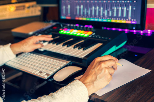 Cuadros en Lienzo male composer hands writing lyric on paper and creating melody on midi keyboard