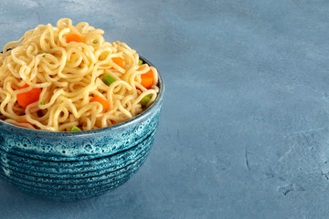 Wall Mural - Instant noodles closeup with vegetables on a slate background, vegan soba with a place for text