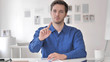 © stockbakers - Young Man Rejecting Offer while Sitting at Workplace