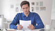 © stockbakers - Young Man Rearing Contract Carefully, Paperwork