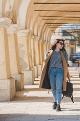 Poster - young pretty fashionable woman walking in brown coat by street