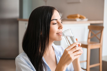 Canvas Print - Beautiful young woman drinking water in kitchen