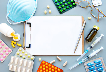 Clipboard, blue medical mask and medicine pills