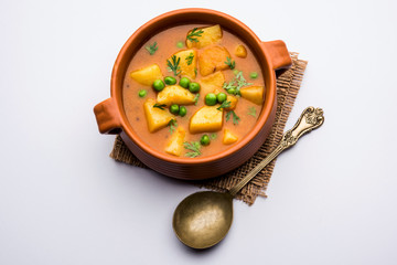 Wall Mural - Aloo Curry Sabzi made using boiled potato with green peas. Served in a bowl or karahi, selective focus