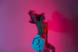 © alones - Fashionable young woman model in stylish youth clothes dancing in the studio with amazing bright neon pink color in disco style. Modern slim sexy girl dancer posing indoors with multi-colored light.