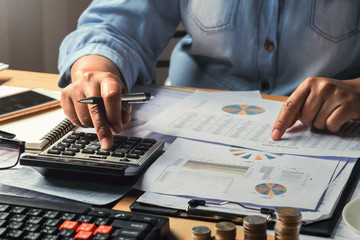 Fototapete - accounting concept. businesswoman working using calculator with money stack in office