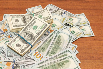 Wall Mural - Many hundred dollar bills on wooden table background texture. bundles of money scattered on the office desk. wealth and income concept