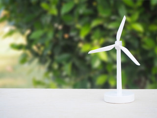 wind turbine or windmill on the white table with blur green tree using for energy background.