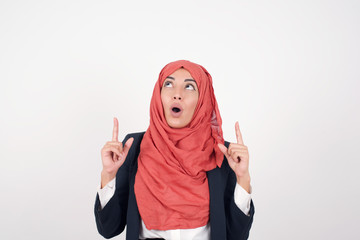 Wall Mural - Portrait of beautiful elegant woman over isolated background being amazed and surprised looking and pointing up with fingers showing something strange.