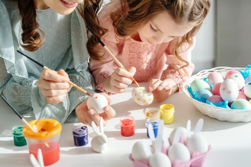 Wall Mural - selective focus of happy mother and cute daughter painting easter eggs near decorative bunnies