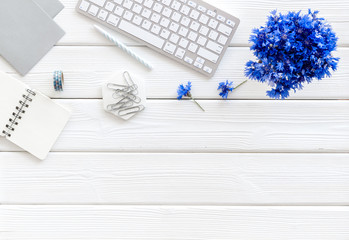 Poster - Summer vibes at work. Office desk with cornflowers bouquet on white wooden background top-down frame copy space