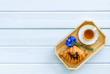 Poster - Breakfast with summer flowers. Tea, croissant and cornflowers on blue wooden background top-down copy space