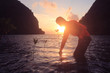© THANAGON - Men playing with sea water in the morning by the beach at sunrise.
