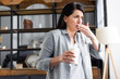 woman with lactose intolerance holding glass of milk and covering mouth