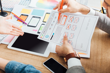 selective focus of designers developing ux design of website near gadgets on table
