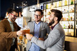 © NDABCREATIVITY - Happy young business men talking and drinking beer in a pub