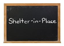 Shelter In Place Written In White Chalk On A Black Chalkboard Isolated On White