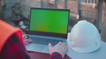 Wall Mural - Hands man engineer using laptop computer with green screen on balcony helmet worker project occupation builder technology mock-up professional male safety device computer slow motion