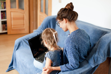 Wall Mural - Distance learning with kids. Remote working from home. Woman and cute child using laptop. Online education, homeschooling webinar, conference room for lessons. Freelancer workplace. Lifestyle moment