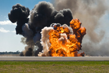 firey explosion with thick black smoke on an airport runway.
