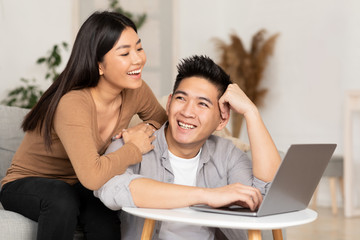 Young asian couple using laptop at their home