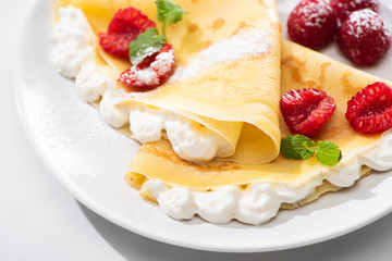 Wall Mural - close up view of tasty crepes with raspberries and whipped cream on plate