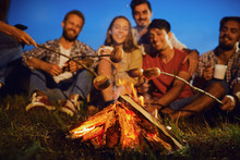 Bonfire At Night On A Background Of Young Smiling People On A Picnic In Autumn