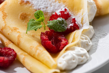 Wall Mural - close up view of tasty crepes with raspberries and whipped cream on plate