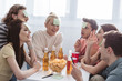 © LIGHTFIELD STUDIOS - smiling friends with sticky notes on foreheads playing name game at table with drinks and chips