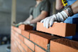 © megaflopp - Two workers making red brick wall at construction site