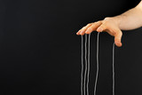 Fototapeta Konie - puppeteer's hand with ropes on fingers control the people mind concept wide web banner