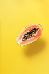 Wall Mural - Halved papaya on yellow background. Top view. Copy space. Summer time. Tropical travel, exotic fruit. Vegan and vegetarian concept