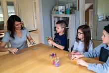 Mother Showing Children How To Build A Catapult Out Of Popsicle Sticks And Rubberbands As Part Of A Homeschool STEM Lesson