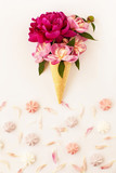 Fototapeta  - Beautiful fresh peonies in ice cream waffle cone on white background. Frame of pink flower petals and color meringue below. Stylish flat lay with flowers and dessert. Floral card design, copy space.