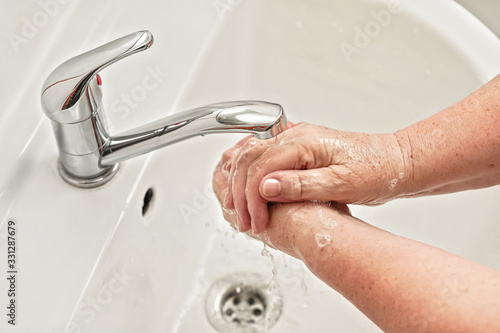 Senior woman washing her hands with soap under tap water faucet. Can be used as hygiene illustration concept during ncov coronavirus / covid 19 outbreak