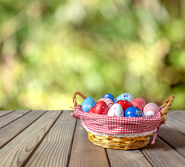 Painted Easter eggs in basket on wooden table